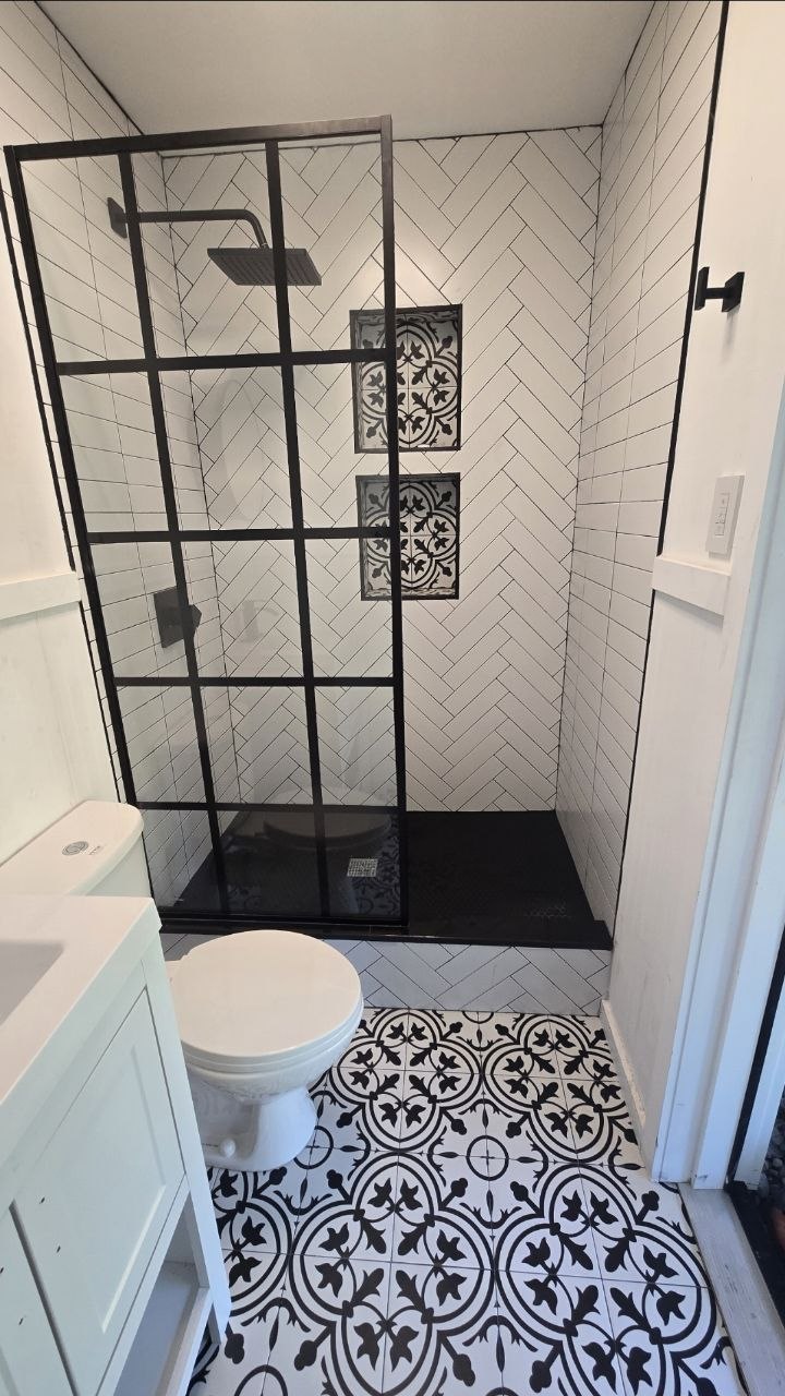 Walk-in shower with herringbone tile and black glass enclosure